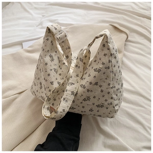 Détail du motif floral sur un sac à bandoulière en toile écrue avec une large sangle