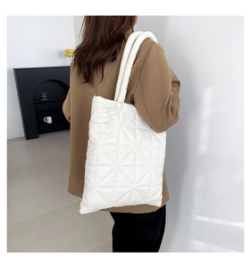 Close-up of white quilted tote bag featuring geometric patterns and thick padded handles