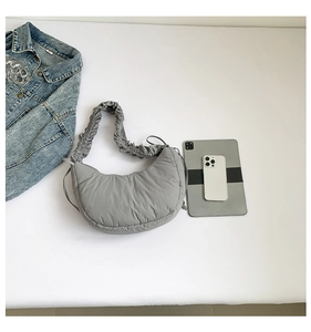 Detail view of the ruched shoulder strap and grey quilted nylon crescent handbag
