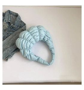 Detail of light blue quilted cloud bag with soft pleated texture and crescent shape