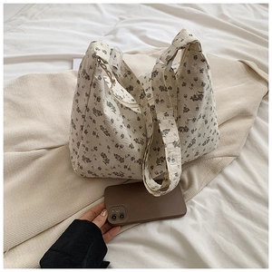Gros plan détaillé du sac cabas en velours côtelé à fleurs mauves sur tissu beige
