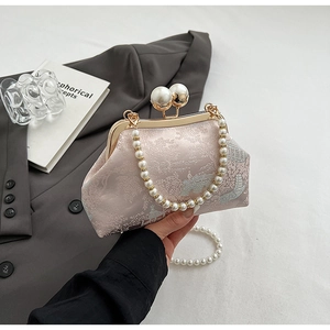 Detail of pink floral brocade handbag with gold clasp and elegant pearl handle strap