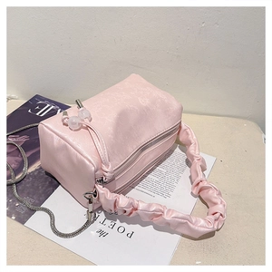 Detailed view of pink pleated satin handbag with floral texture and silver chain