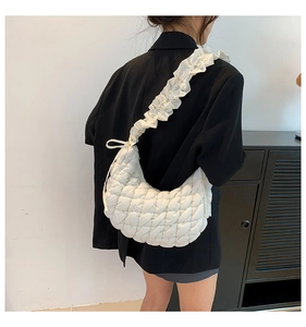 Detail of ivory quilted dumpling bag showing ruffled shoulder strap and puffy texture