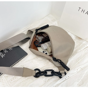 Detail view of the canvas chest bag interior holding a phone, sunglasses, and cosmetics