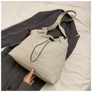 Detail of off-white drawstring tote bag with plush charm on a grey suit jacket