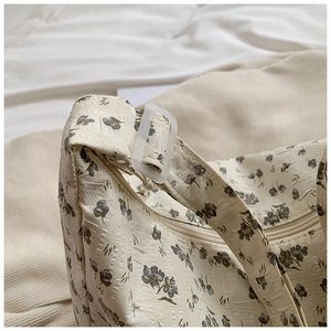 Détail du sac cabas en toile fleurie montrant la texture, le zip et la boucle