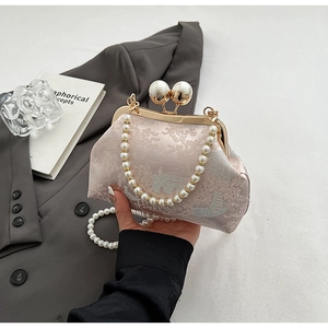 Close-up of pink jacquard handbag with pearl kiss-lock and elegant pearl handle