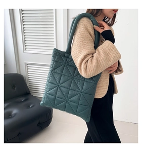 Close-up of a quilted tote bag in dark green fabric with triangle stitching detail