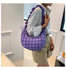 Detail of purple quilted shoulder bag featuring trendy ruffled strap and soft texture