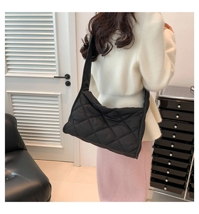 Détail d'un sac à bandoulière noir matelassé avec motif à losanges sur un mannequin