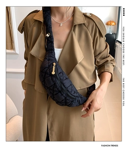 Detailed shot of black quilted nylon chest bag with golden zipper on khaki coat
