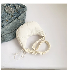 Detail of creamy white crescent shoulder bag with ruched strap and drawstring