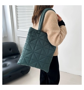 Detailed view of dark teal quilted puffer tote bag featuring geometric triangle stitching