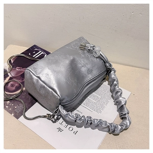 Macro shot of silver textured handbag with metallic chain and pleated leather handle