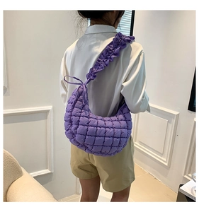 Detail view of purple quilted dumpling bag with ruffled shoulder strap and bow ribbon