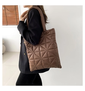 Side view of woman carrying a brown quilted tote bag with padded triangular stitching