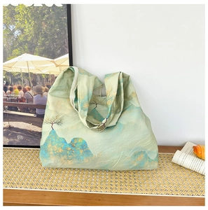 Detailed close-up of light green canvas tote bag featuring scenic ink landscape prints