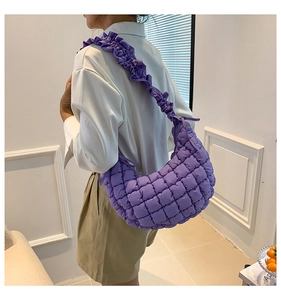 Detail of purple quilted dumpling bag with ruffled shoulder strap shown on a model