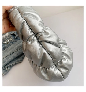 Detail of silver pleated cloud bag in soft PU leather held against denim jacket background