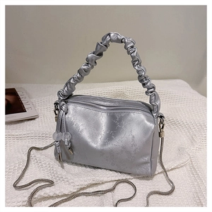 Detailed shot of silver pleated handbag with embossed floral texture and metal chain strap