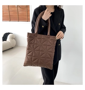 Detailed close-up of brown quilted puffer tote bag with triangular stitching pattern