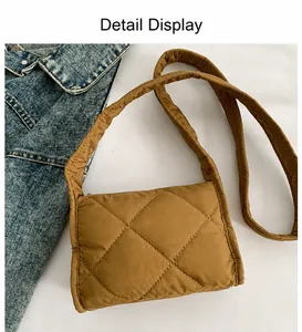 Detail van de bruine gewatteerde nylon crossbodytas met ruitstiksels en brede schouderriem