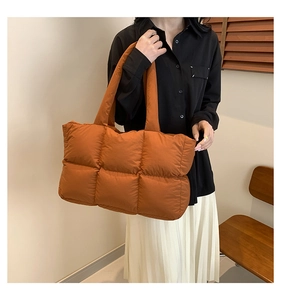 Detailansicht einer orangebraun gesteppten Puffer-Tragetasche am Modell zur Größenangabe