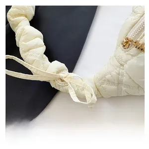 Close-up of cream quilted bag with adjustable ruched strap and gold metal zipper
