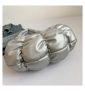 Detail of silver metallic cloud bag with quilted puffy texture next to denim jacket