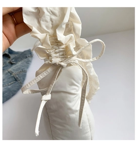Detail of white pleated shoulder bag featuring drawstring closure and soft fabric