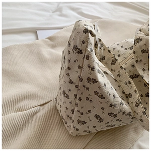Détail du motif floral avec texture plissée sur un sac à bandoulière crème