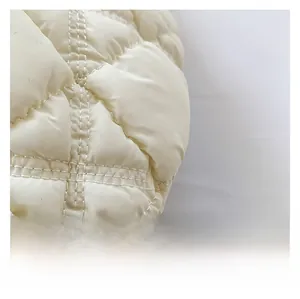 Close-up of premium beige quilted fabric showing diamond stitch patterns and puffed texture