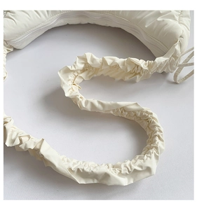 Close-up of the pleated scrunchie strap and soft nylon texture on a cream cloud bag