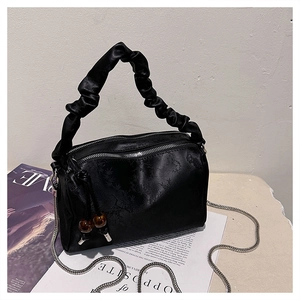 Detail of black silk satin handbag with bamboo texture and scrunchie handle with chain