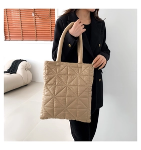Detail showing beige quilted nylon tote bag texture and soft padded handle design