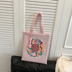 Pink woven tote bag with traditional Chinese dragon embroidery and tassel decoration
