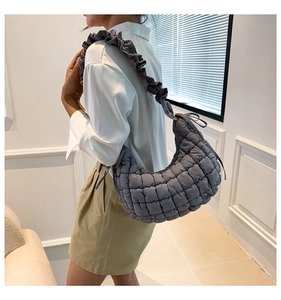 Quilted dark grey half-moon shoulder bag with ruffled strap shown on a model