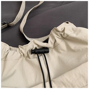 Close-up of cream white tote bag with adjustable black drawstring and spring buckle