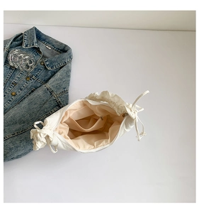 Detail view of white ruched hobo bag with beige lining and inner zipper pocket
