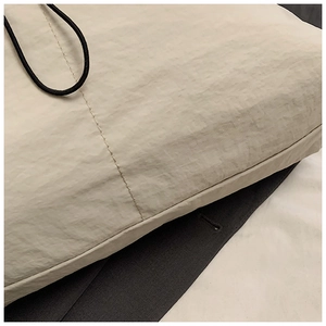 Close-up of beige nylon tote bag showing precision stitching and fabric texture