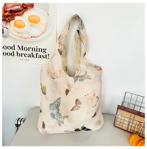 Close-up of cream canvas tote bag featuring a vintage hand-painted butterfly pattern