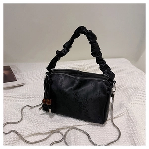 Detailed shot of a black pleated handbag with silver chain and dark bead charms