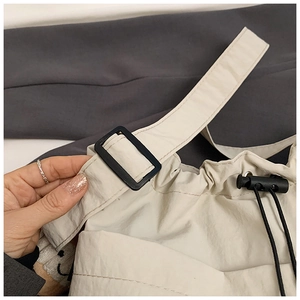 Detail of beige nylon tote showing waterproof fabric texture and black toggle fastener