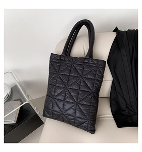 Detail of black quilted puffer tote bag with geometric stitching on a leather chair