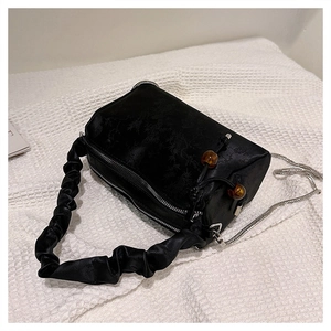 Detail of black satin cylinder bag with floral texture and silver chain strap