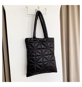Detail of black quilted puffer tote bag with soft padded texture and rhombus stitching