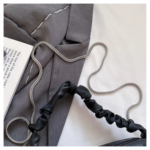Detail of black pleated scrunchie handle bag with silver chain on a grey blazer coat