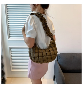 Close-up of olive green quilted hobo bag with puffy texture and ruffled shoulder strap