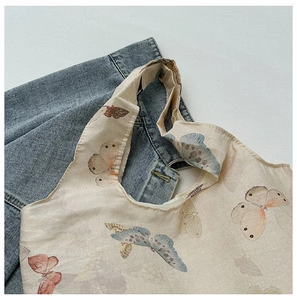 Close-up of the artistic butterfly print on a light beige canvas tote bag surface